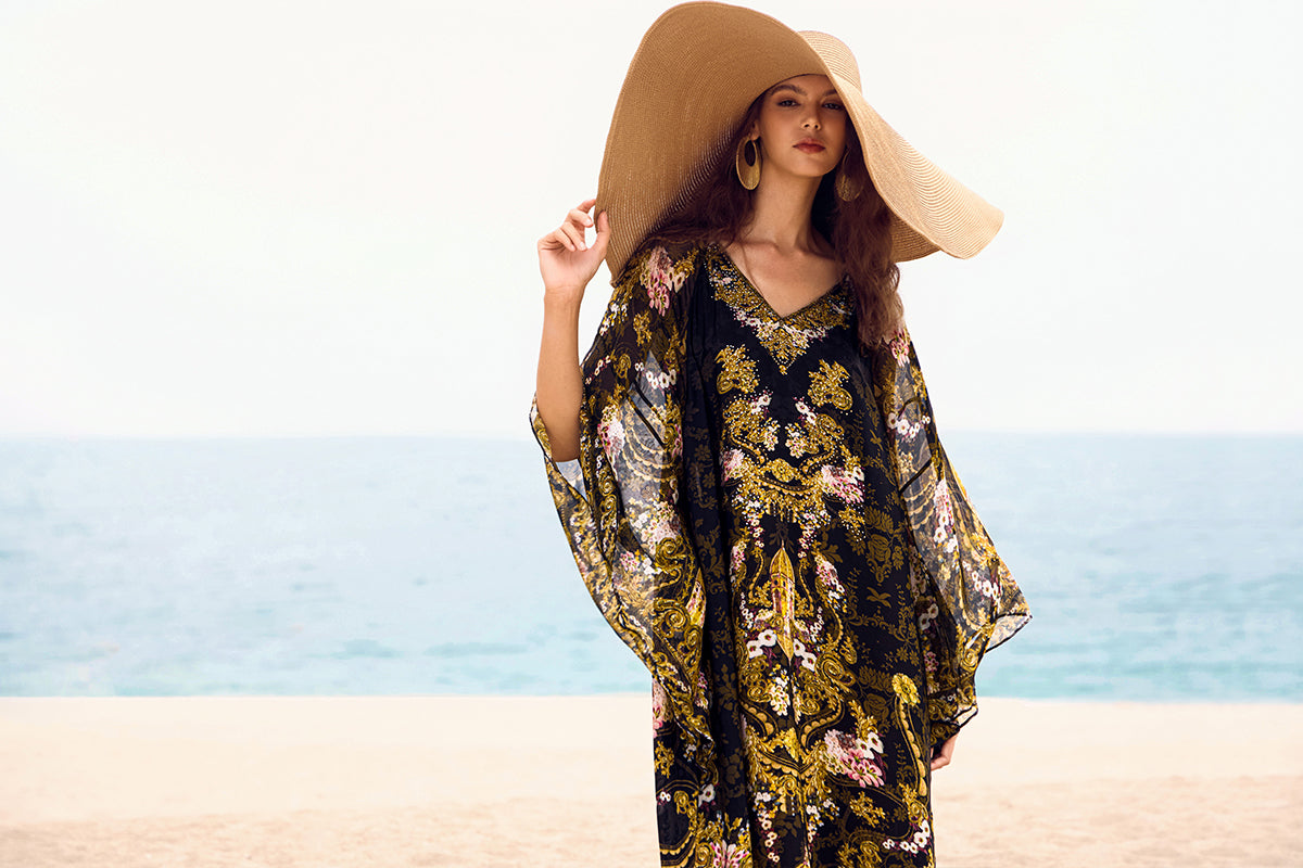 Woman wearing a floral resort casual dress and wide-brim sun hat on the beach