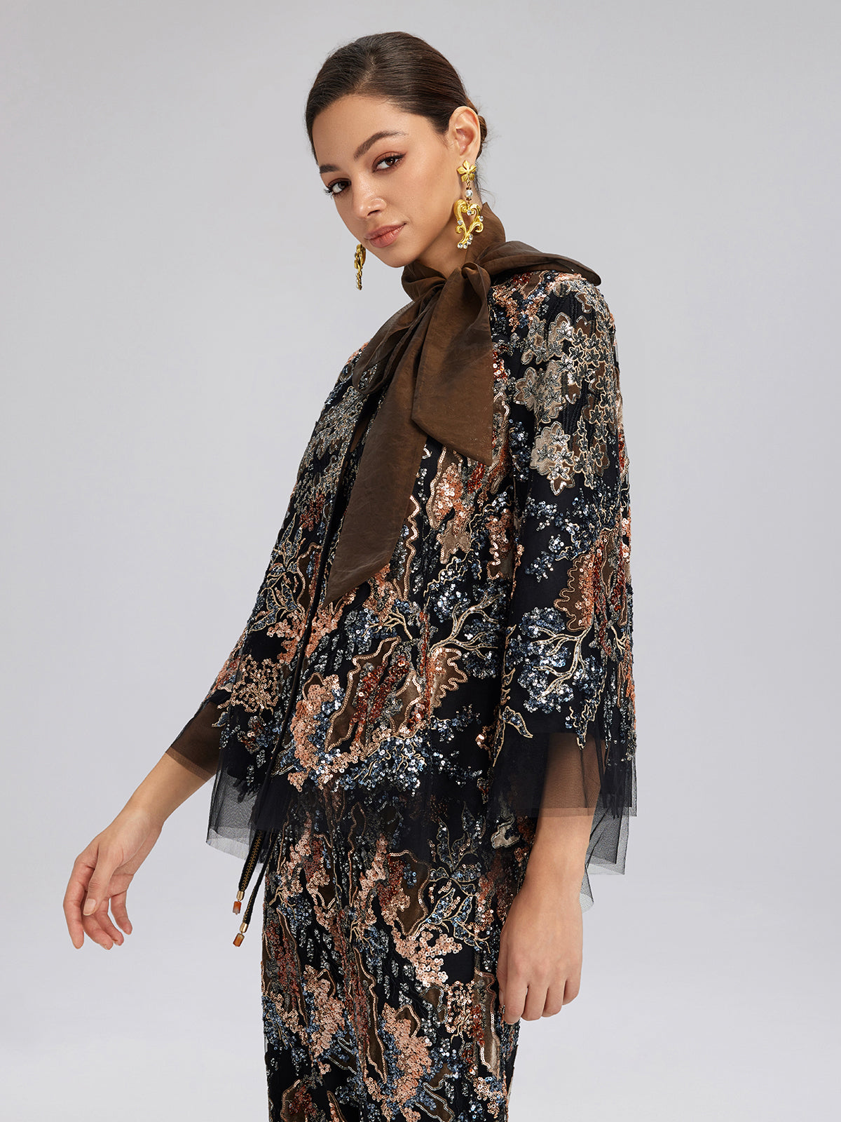 Elegant woman in a black sheer embroidered jacket with floral patterns and matching skirt outfit