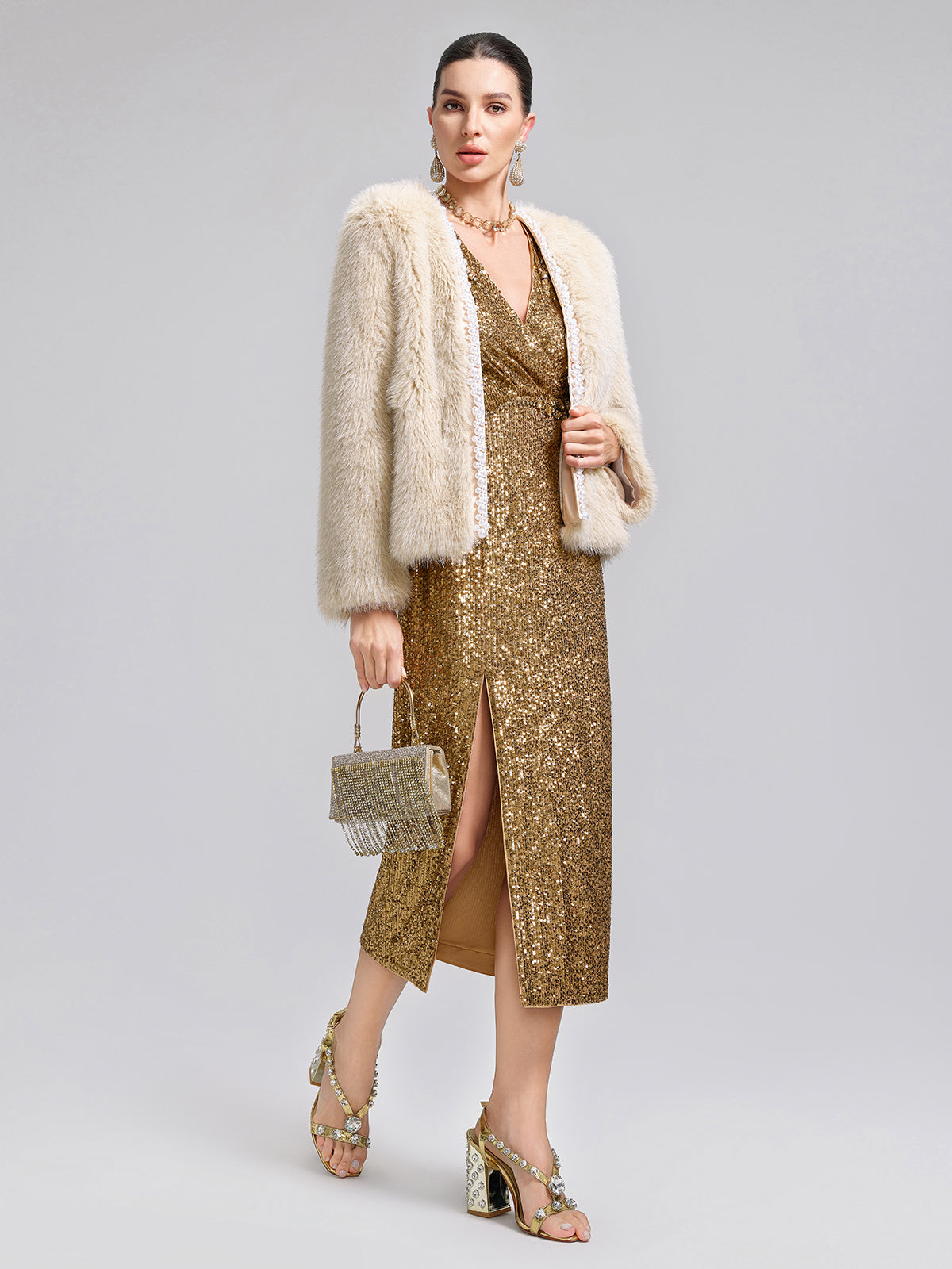 Woman wearing a gold sequin midi dress with a cream faux fur jacket and metallic accessories