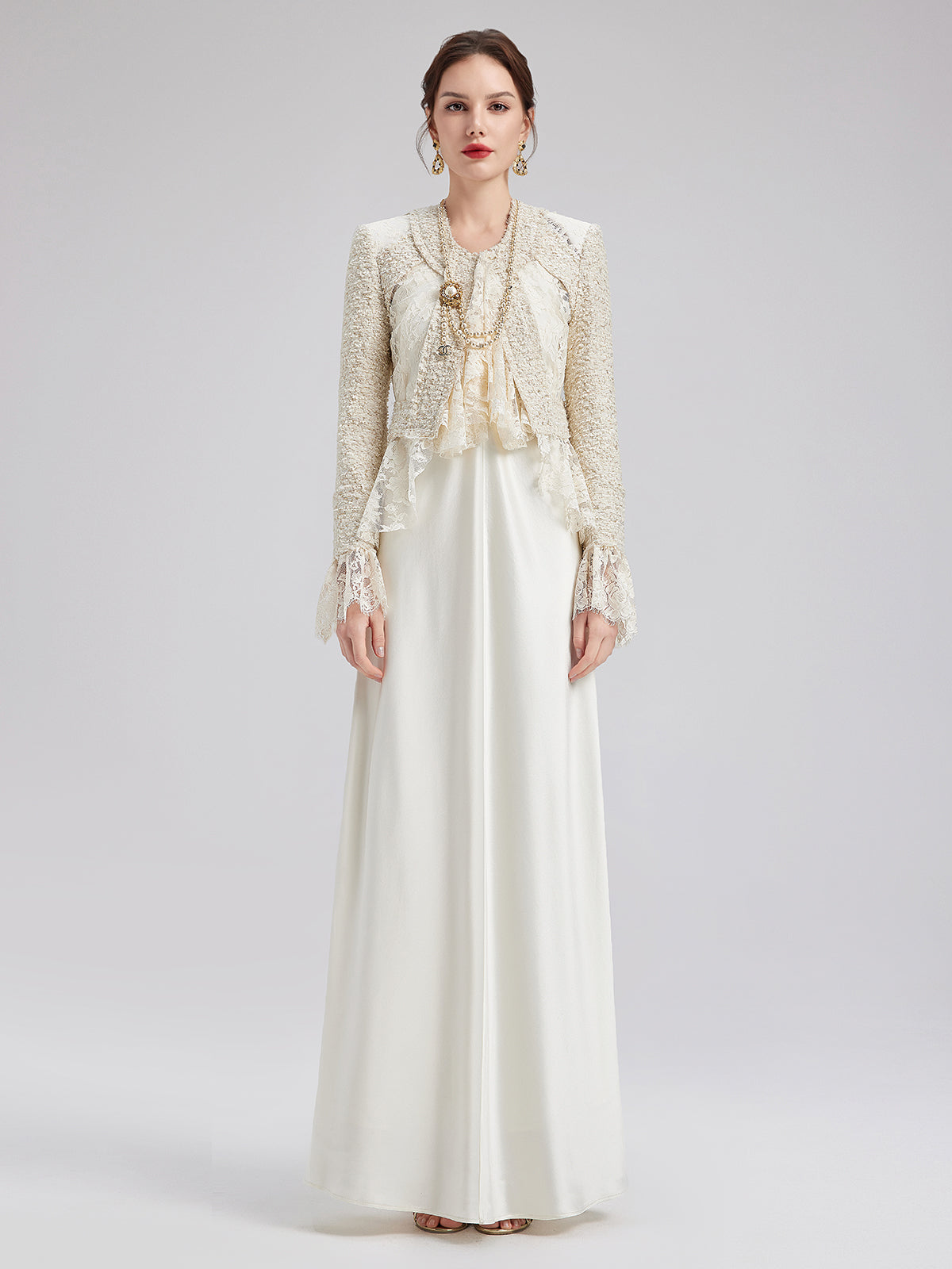 Elegant woman in a white embellished cropped jacket and flowing floor length white dress outfit