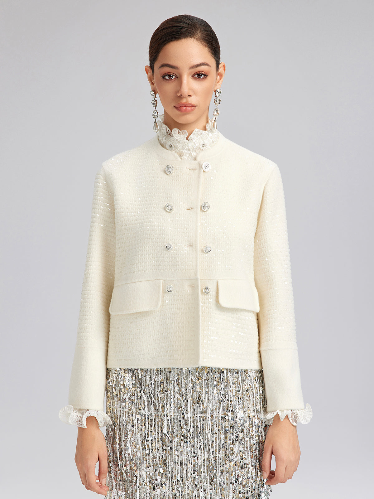 Woman wearing an ivory textured jacket with crystal buttons and a silver sequin skirt