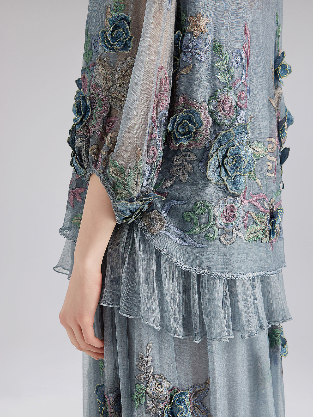Blue embroidered sheer blouse detail with floral patterns and layered ruffles