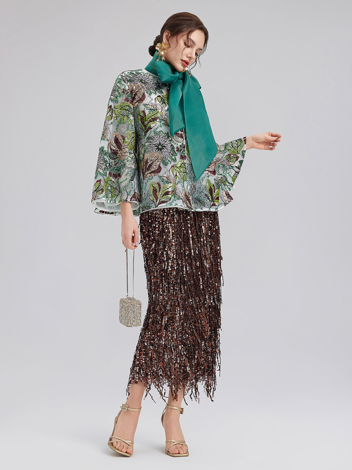 Elegant woman in a green floral blouse with a matching scarf and sparkling sequin fringe skirt outfit