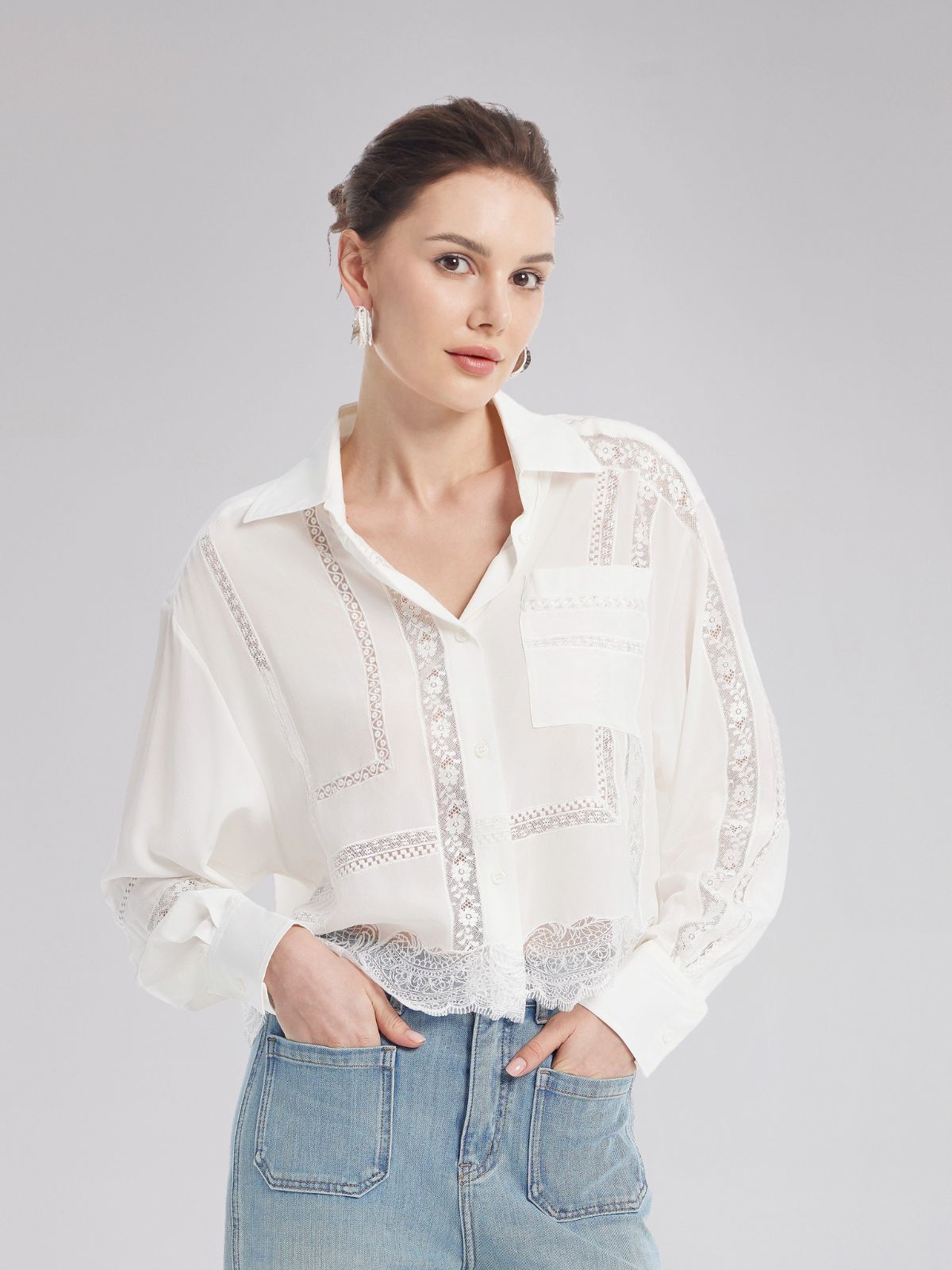 Elegant woman in a white blouse featuring delicate embroidery, lace panels, and a relaxed fit