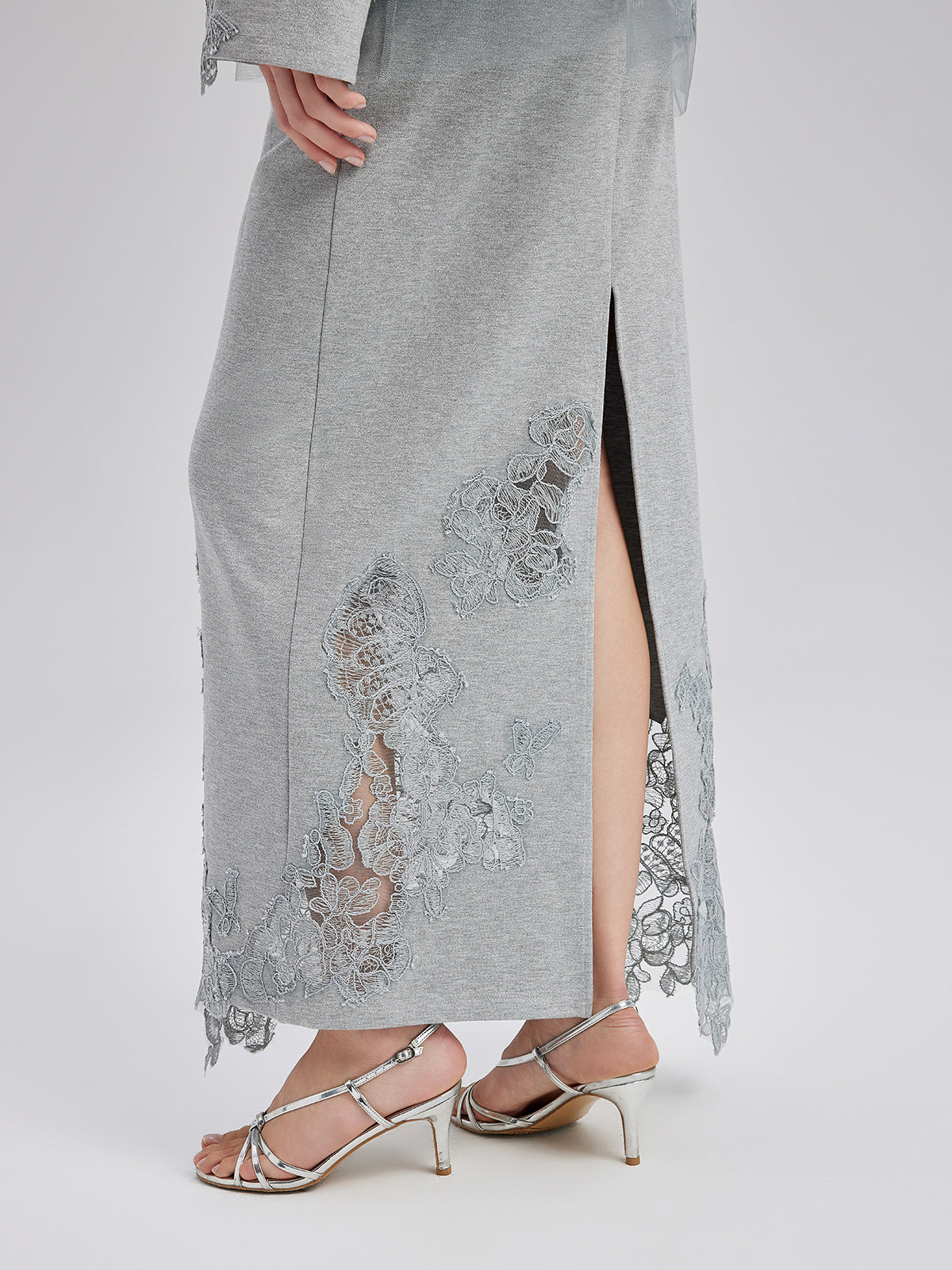 Detailed close-up of a silver midi skirt featuring delicate floral embroidery, lace accents, and elegant slit detailing
