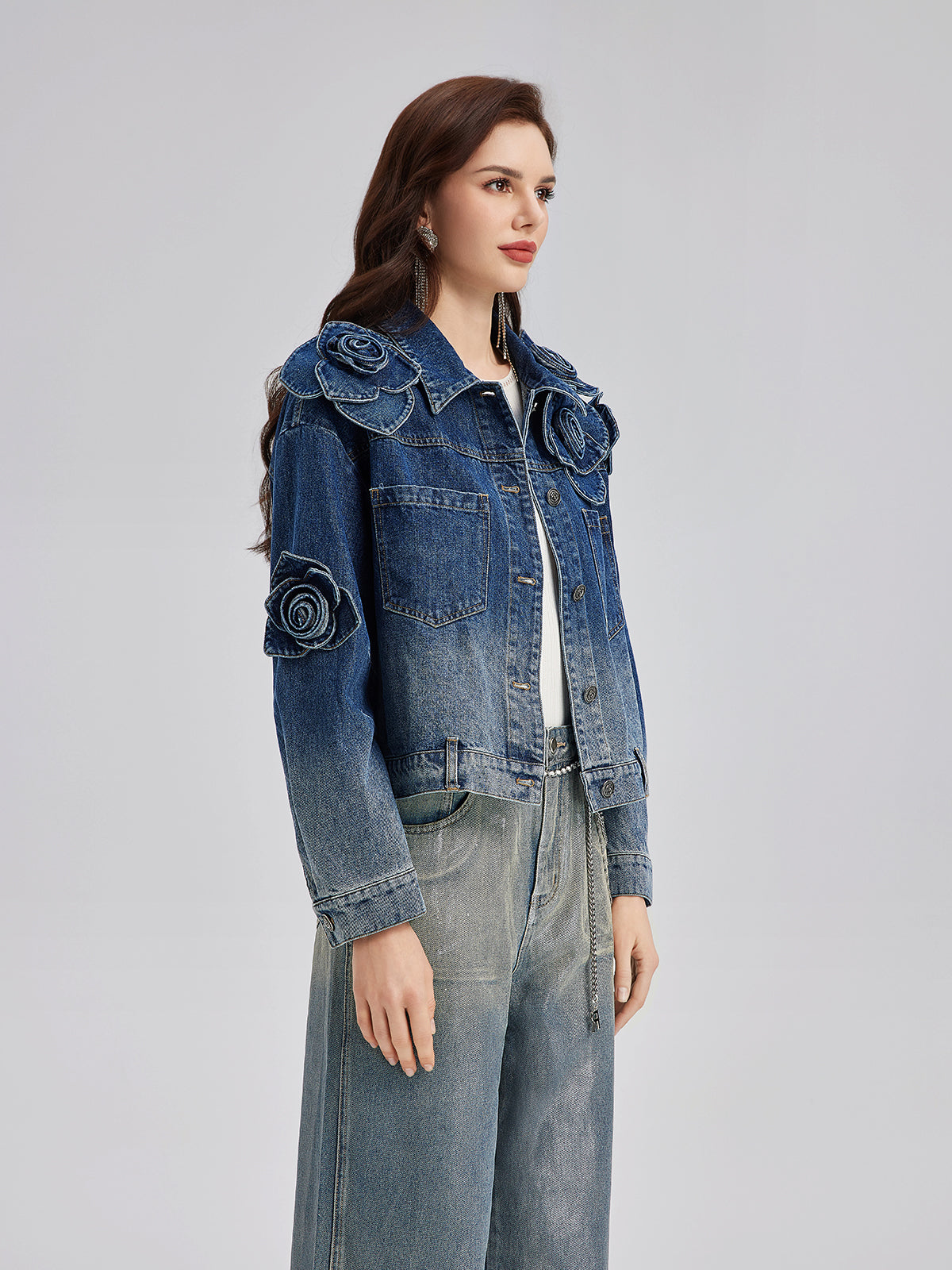 Elegant woman in a blue denim jacket featuring embroidered floral embellishments and structured design