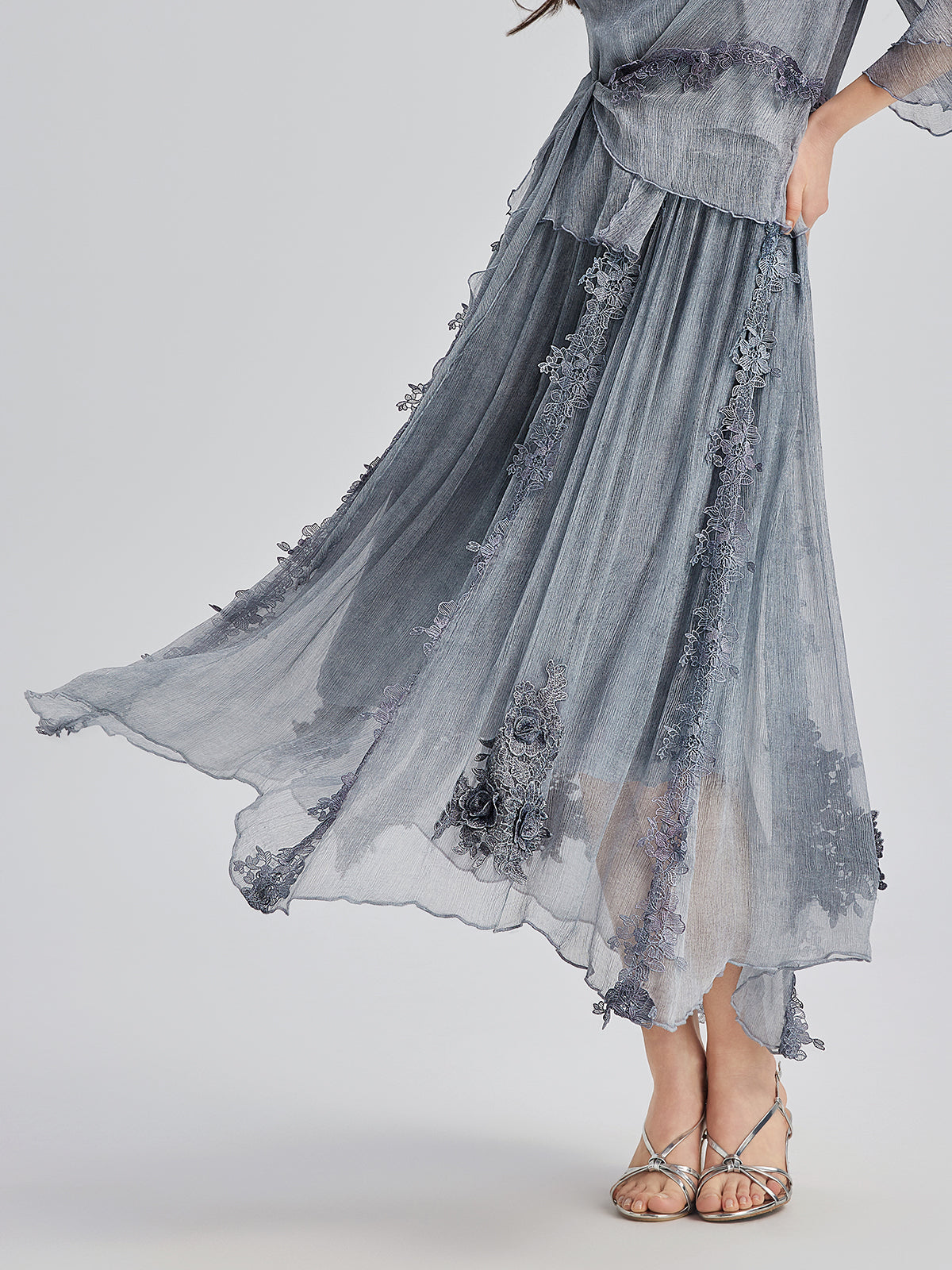 Detailed close-up of a light blue sheer midi skirt featuring floral embroidery, layered fabric, and elegant flowing silhouette