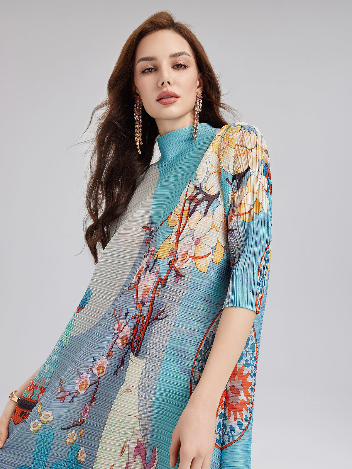 Elegant woman in a turquoise floral pleated dress with artistic print design and short sleeves