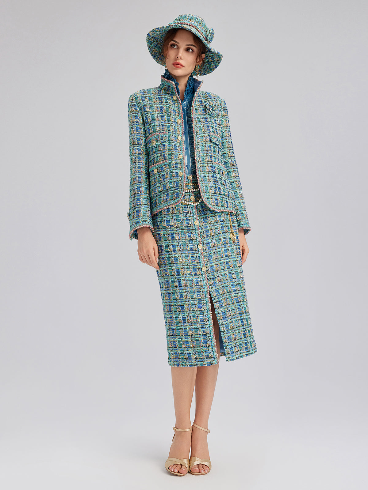 Elegant woman in a blue textured tweed coat and skirt set featuring a coordinated hat and sophisticated tailoring