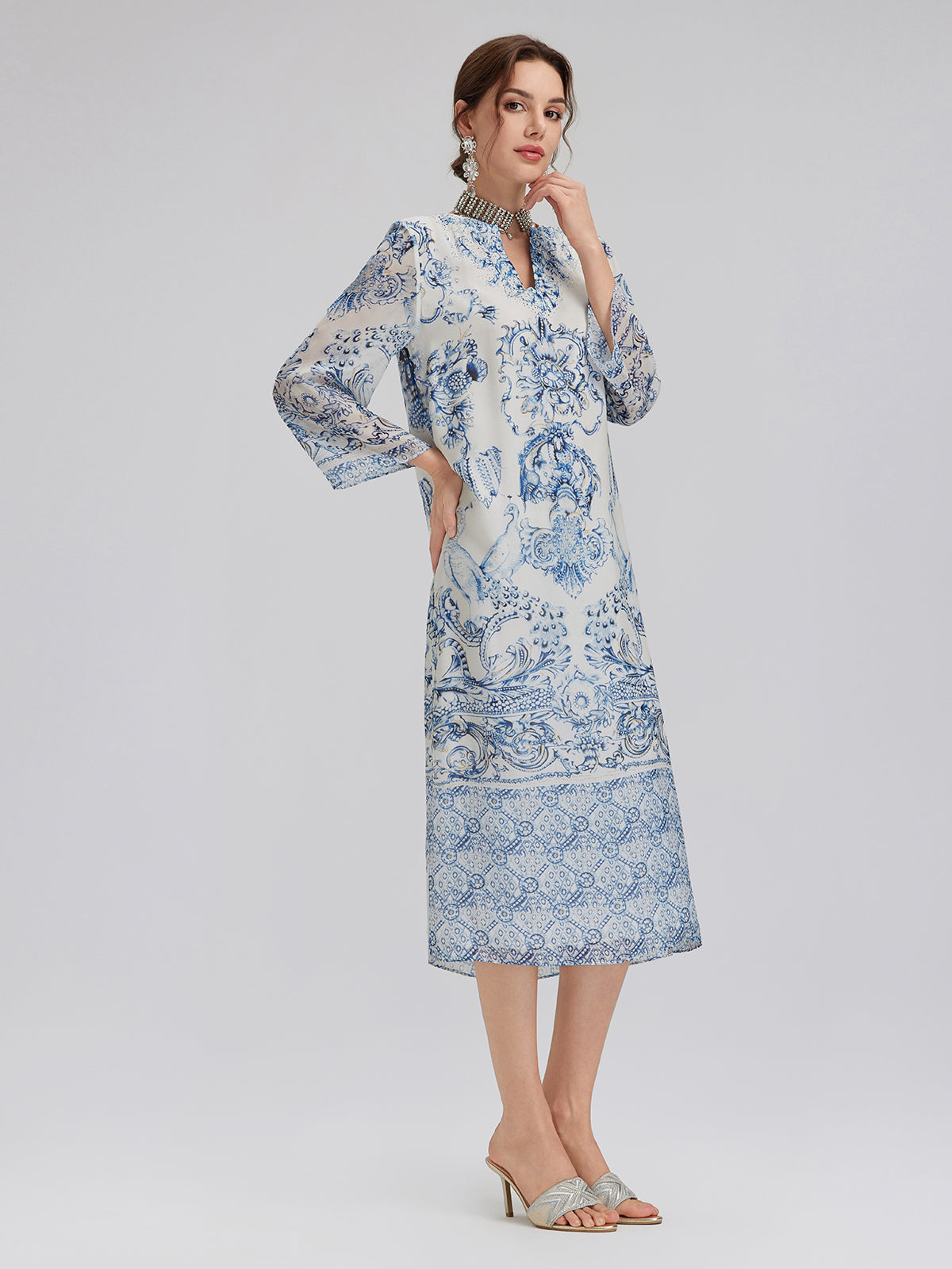 Elegant woman in a blue and white embroidered floral midi dress with long sleeves